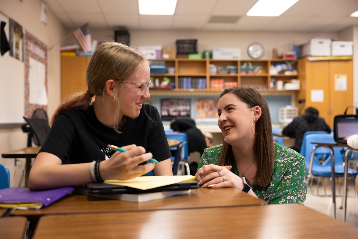 College student helping younger student in classroom